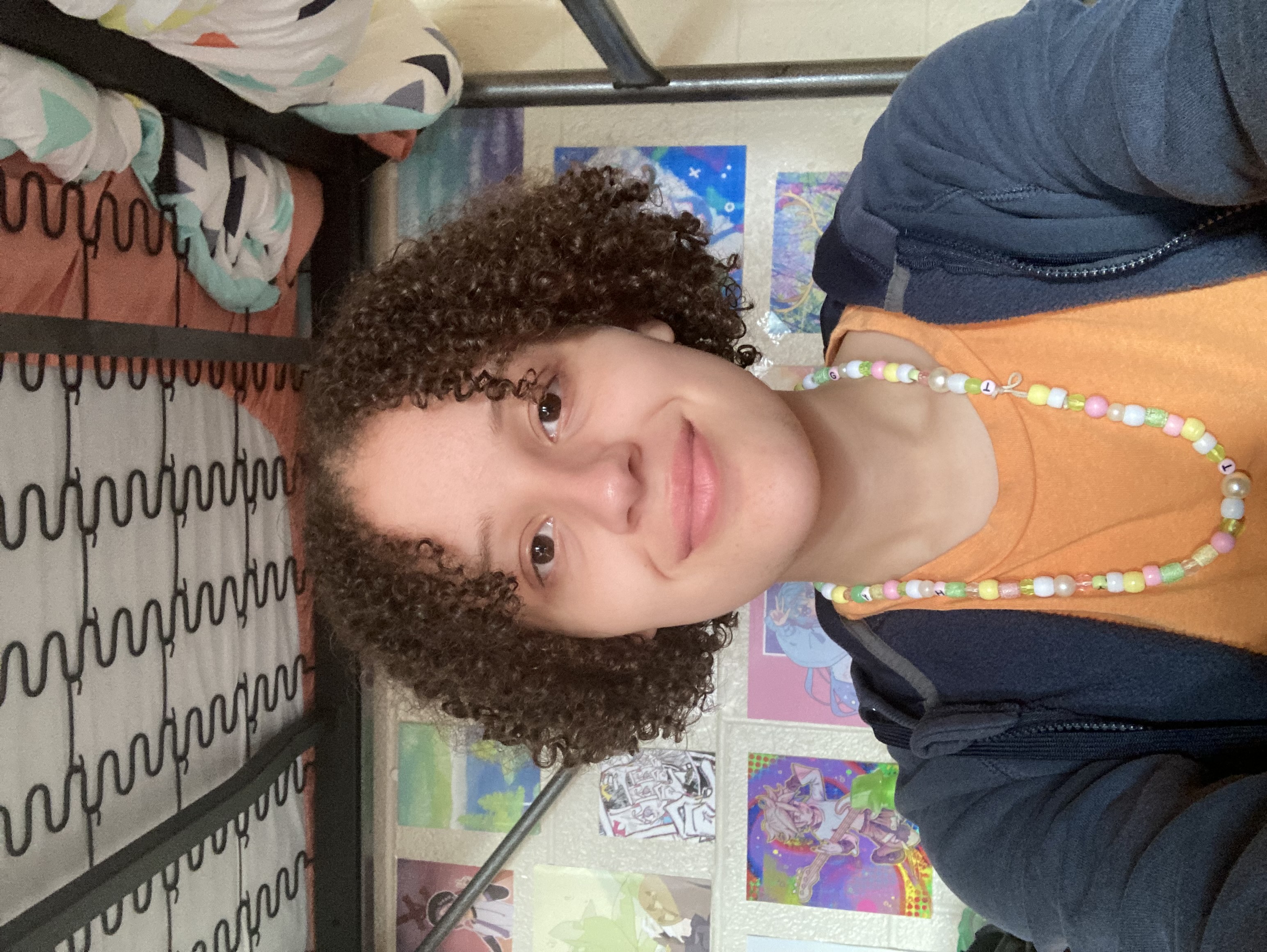 Selfie of Gabrielle in her dorm room with several posters visible in background.