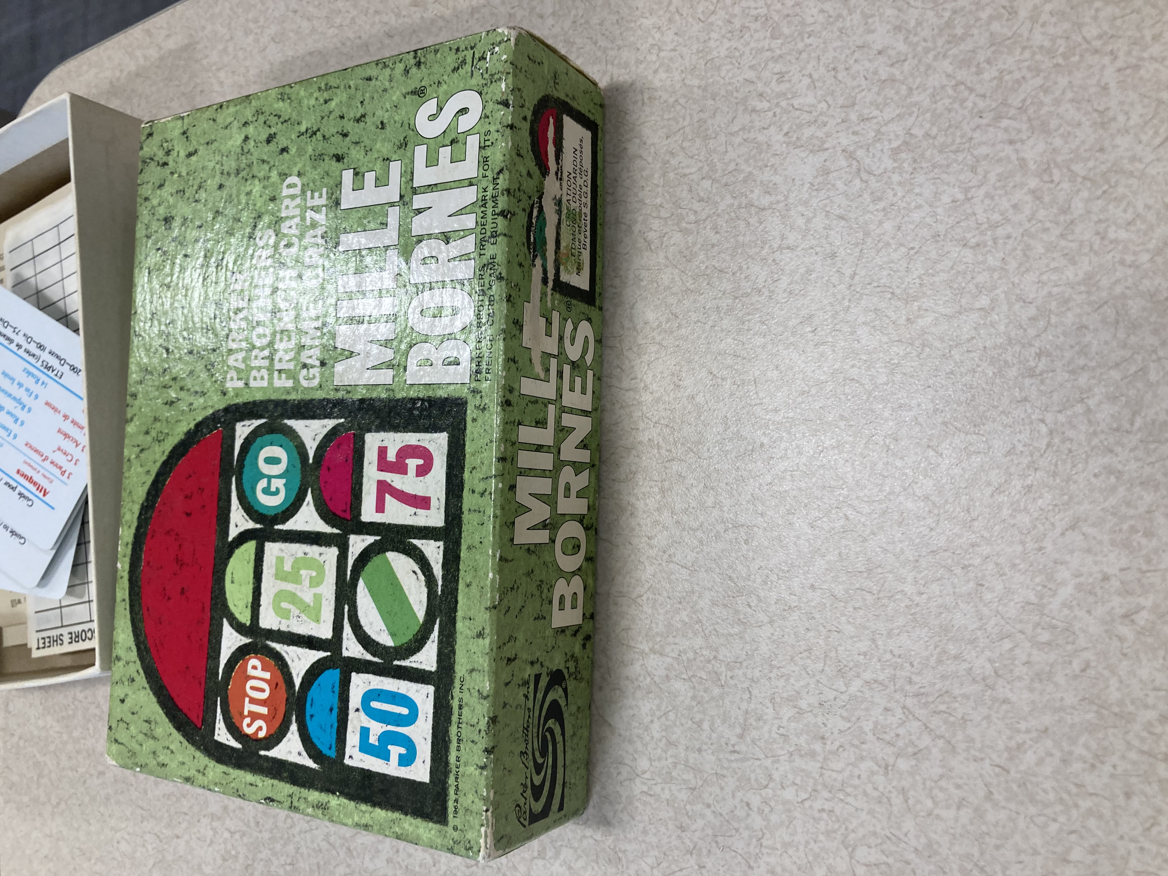 Photo of the Mille Bournes box reading Parker Brothers French Card Game Craze Mille Bournes The box has several road sign symbols as well