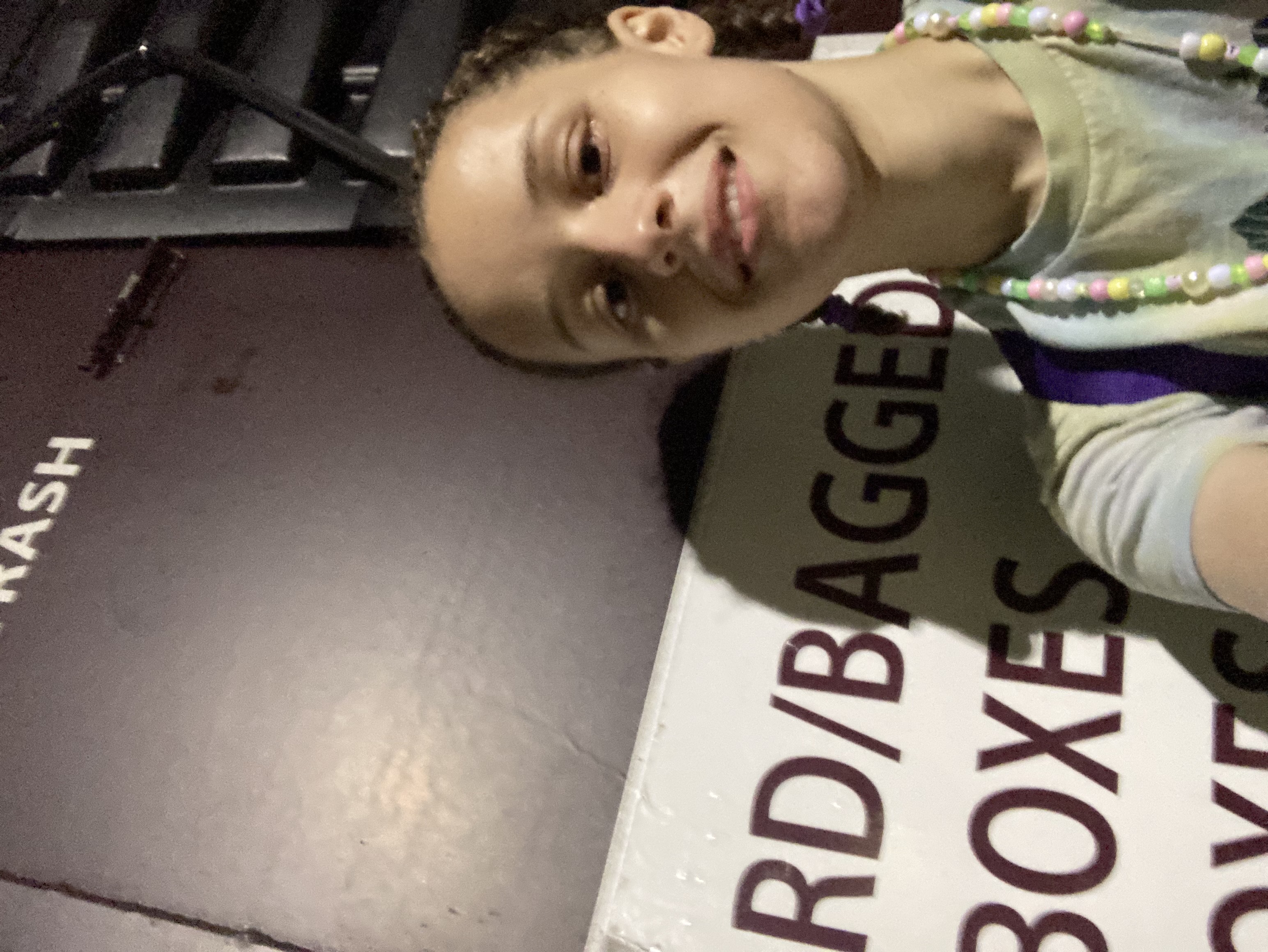 Picture of Gabrielle standing next to an outdoor recycling bin at night